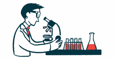 A researcher looks into a microscope near a rack of vials and a beaker.