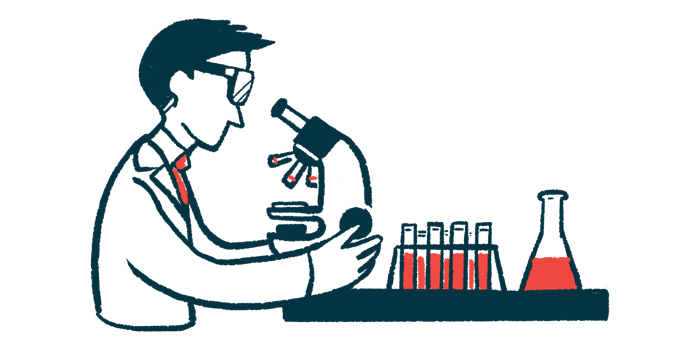 A researcher looks into a microscope near a rack of vials and a beaker.